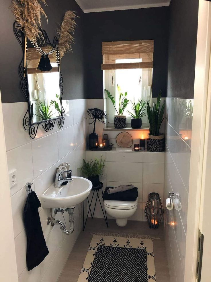 a bathroom with a toilet, sink and plants on the wall in front of it