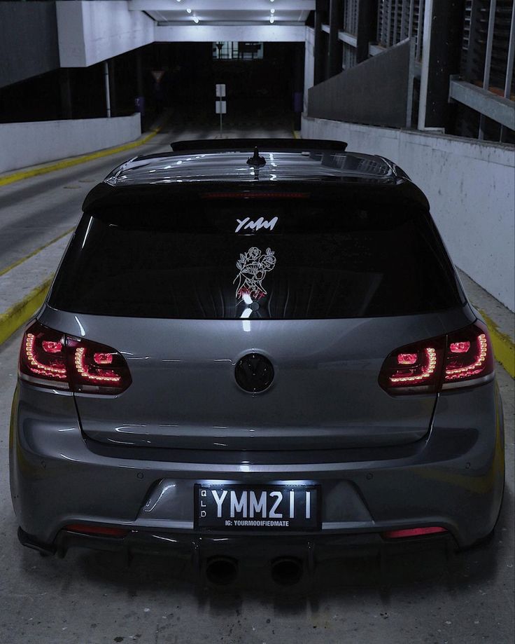 the back end of a car parked in a parking garage with its lights turned on