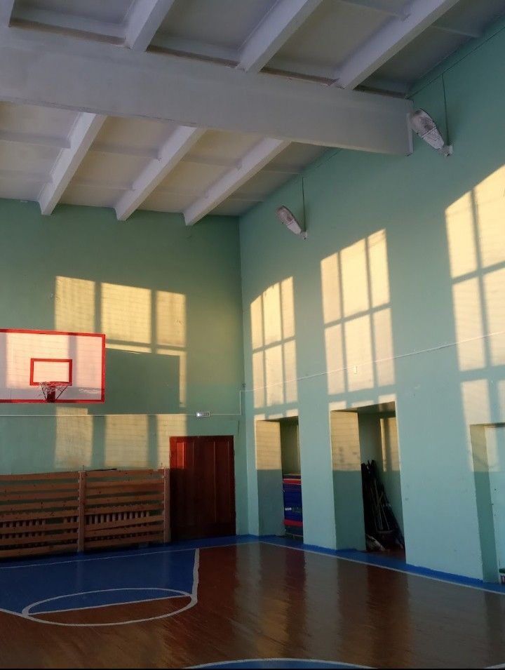 an indoor basketball court with sun shining through the windows and wooden benches on the side