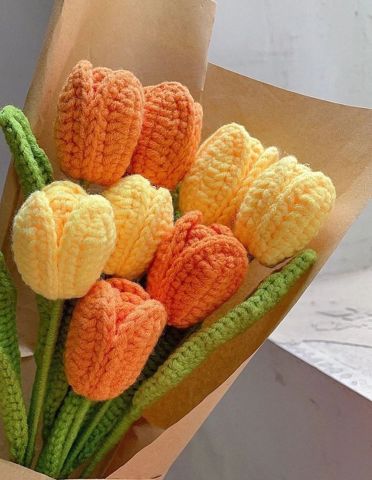 a bouquet of crocheted flowers in a paper bag