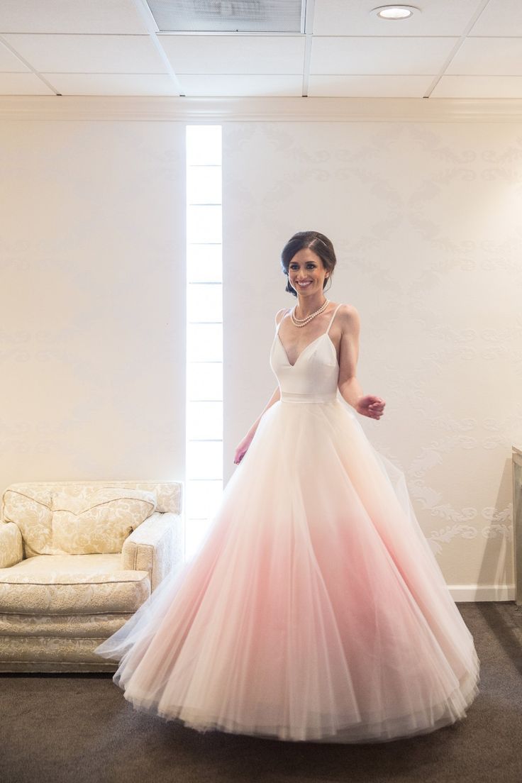 a woman in a pink and white wedding dress posing for the camera with her hand on her hip