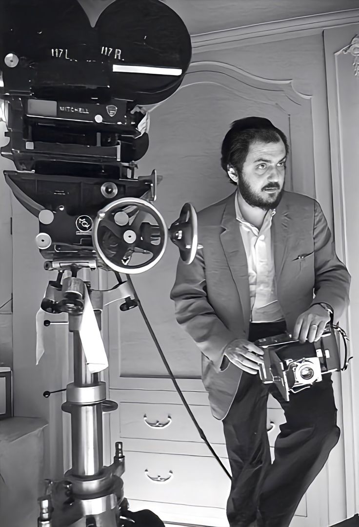 black and white photograph of a man holding a camera in front of a video camera