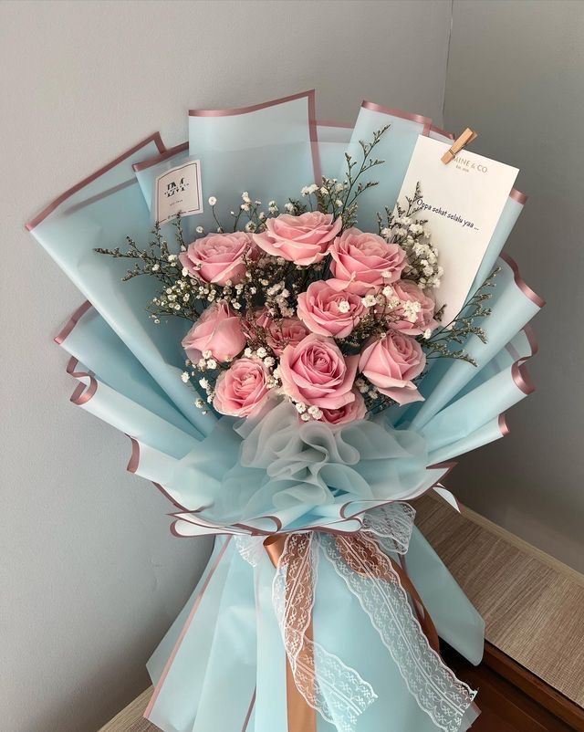 a bouquet of pink roses wrapped in blue paper