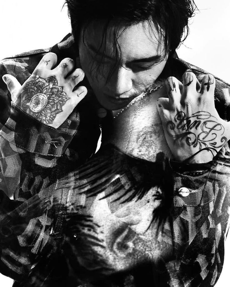 a man with tattoos holding his hands to his face