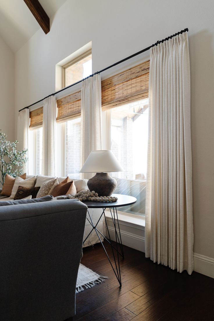 a living room filled with furniture and a window covered in white drapes next to a couch