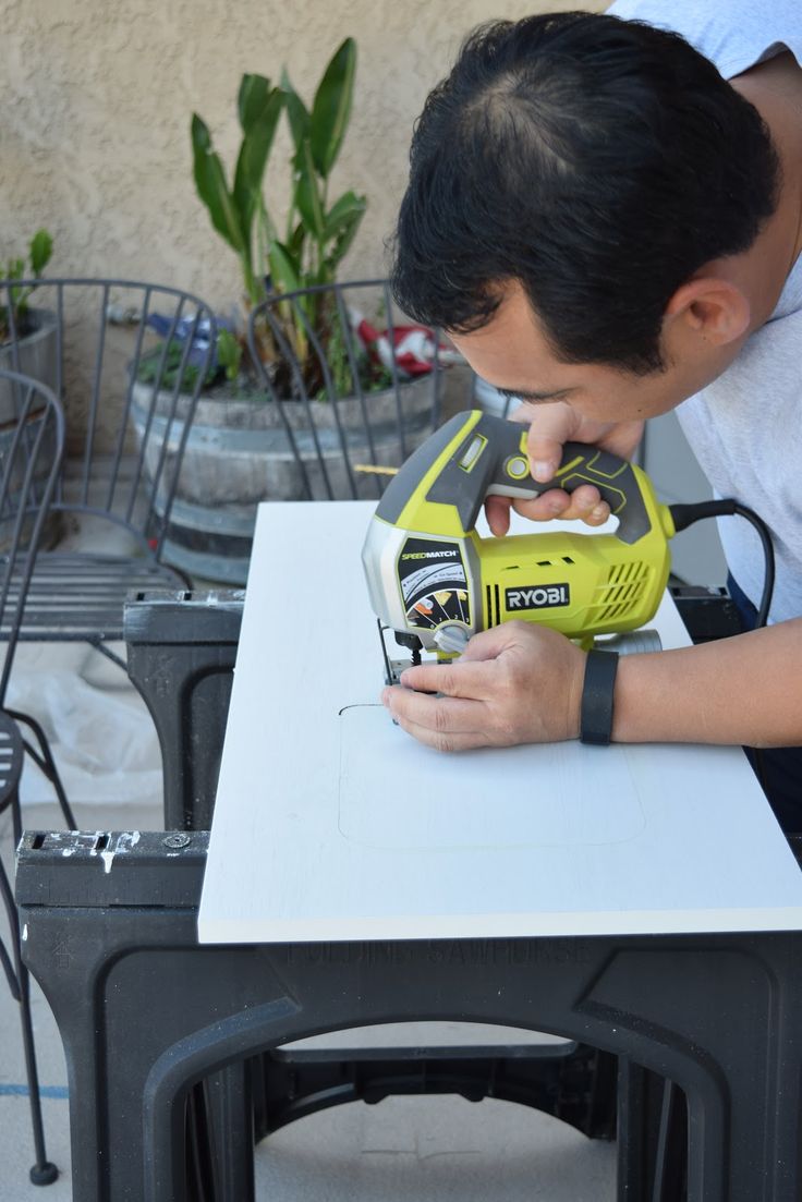 a young man is using a yellow and black machine on a white table with plants in the background