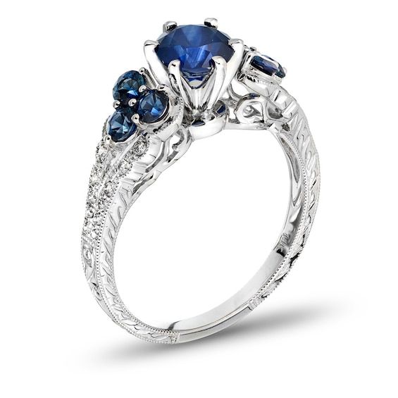 three stone engagement ring with blue sapphires and diamonds on the sides, set in white gold