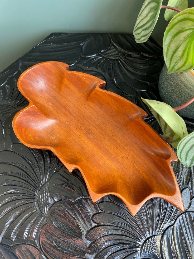 a wooden platter sitting on top of a table next to a potted plant