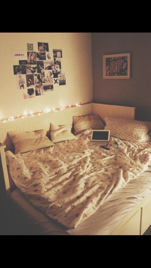 an unmade bed with several pictures on the wall above it and a lap top computer