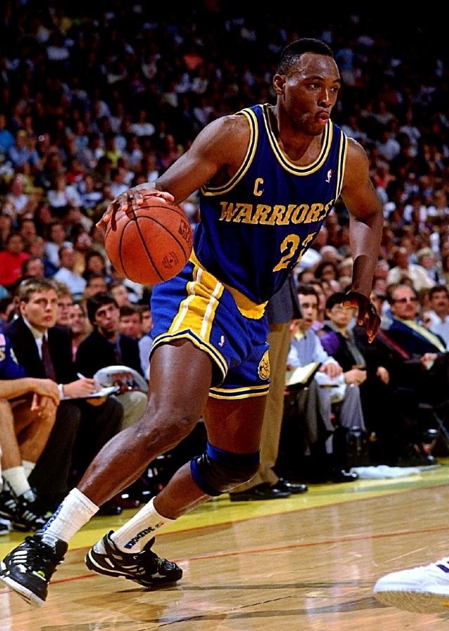 a basketball player dribbles the ball while running down the court with his foot