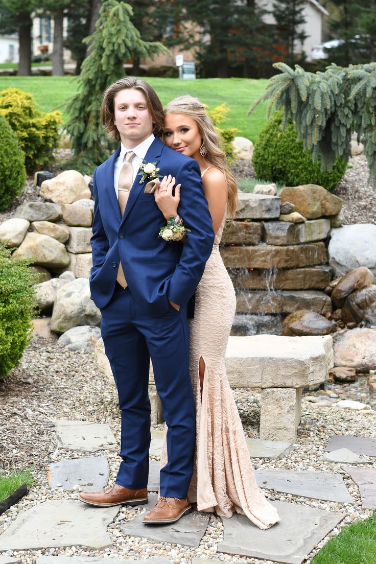 a man in a blue suit and tie standing next to a woman wearing a pink dress