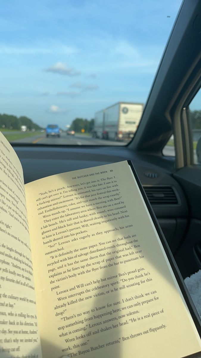 an open book sitting in the passenger seat of a car next to a window and dashboard