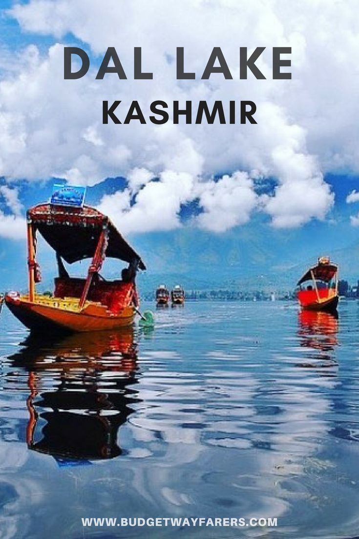 two boats floating on top of a lake under a blue sky with clouds in the background