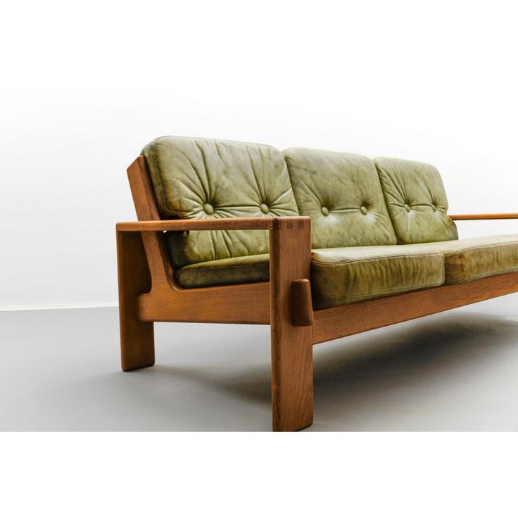 a green leather couch sitting on top of a wooden frame