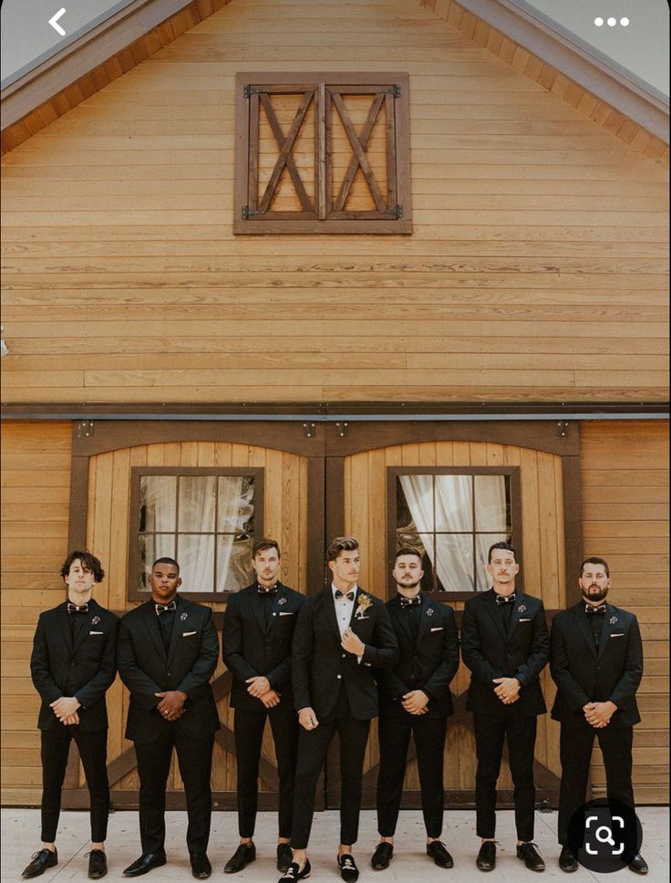 a group of men standing next to each other in front of a wooden building with windows