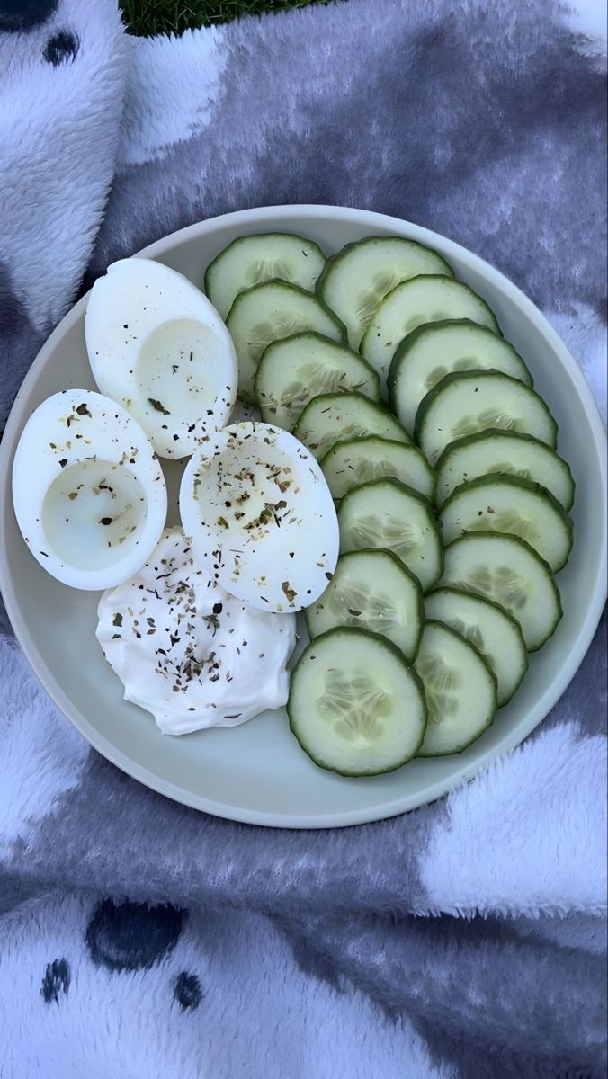 cucumber slices and hard boiled eggs on a white plate with a gray towel