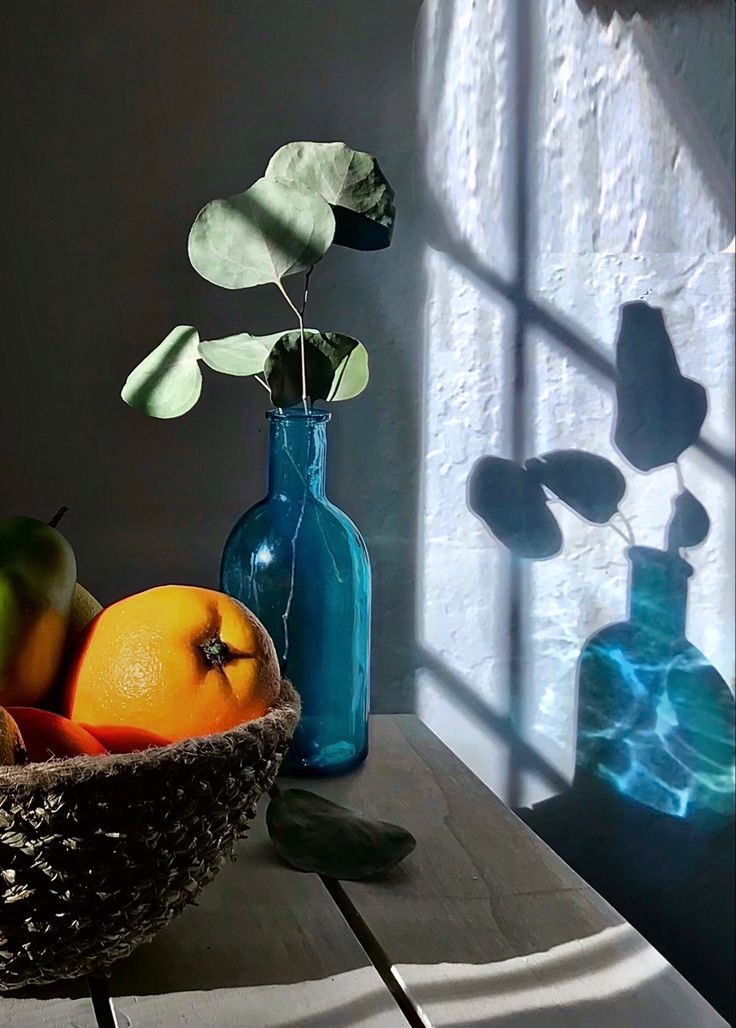 a basket filled with fruit sitting on top of a table next to a blue vase