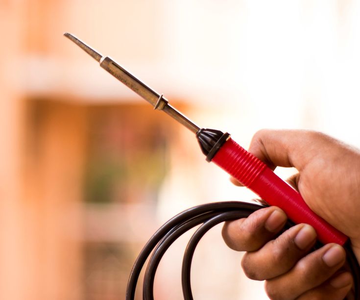 a person holding a pair of scissors in their hand with a cord attached to it