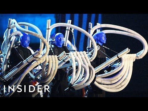 blue man group performing on stage with hoses in front of their faces and the words inside