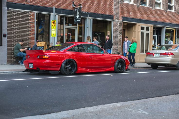 a red car parked on the side of a street next to a tall brick building