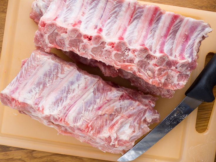 two pieces of raw meat sitting on top of a cutting board next to a knife