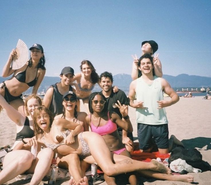 a group of people sitting on top of a beach next to each other in bikinis