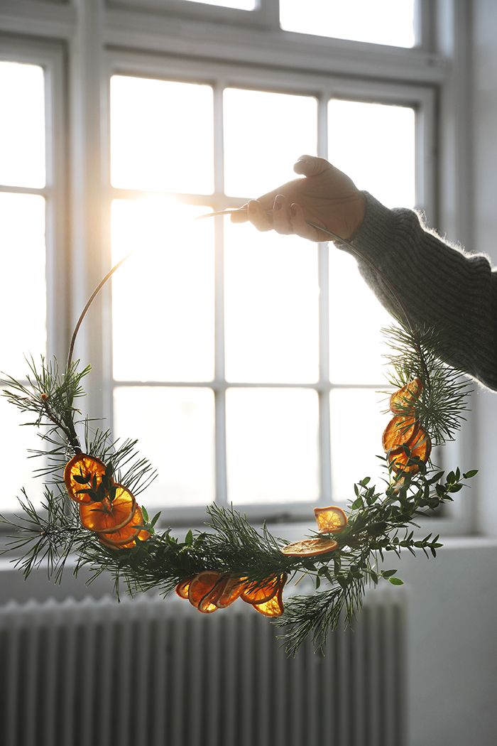 a person holding a candle in front of a window with pine cones and lights on it