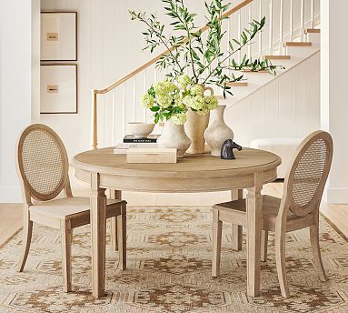 a dining room table with two chairs and a vase on the table next to it