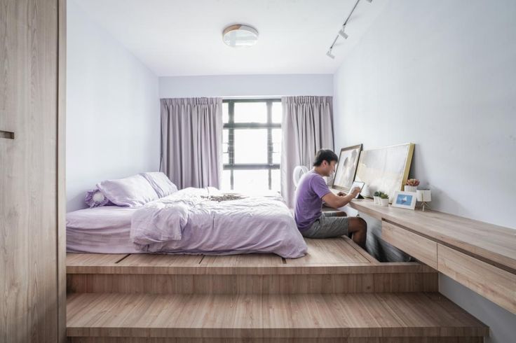 a man sitting on top of a bed in a bedroom next to a wooden staircase