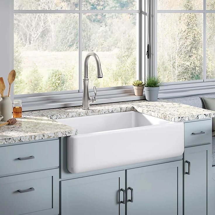 a white kitchen sink sitting under a window next to a counter top with utensils