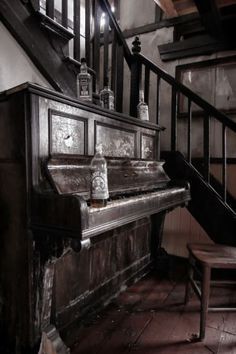 an old piano sitting in front of a stair case