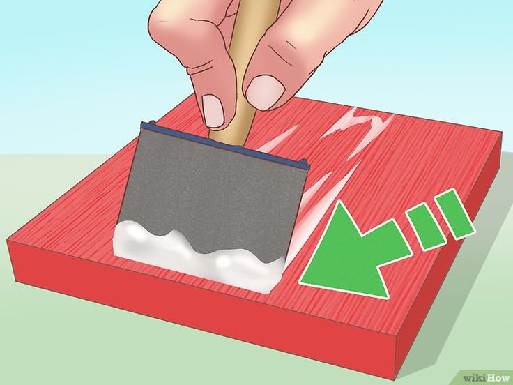 a person is using a knife to cut paper on a piece of red wood with green arrows