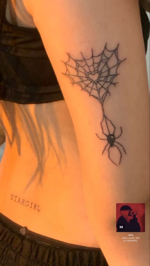 a woman with a spider web tattoo on her arm and the word stargirl written in black ink