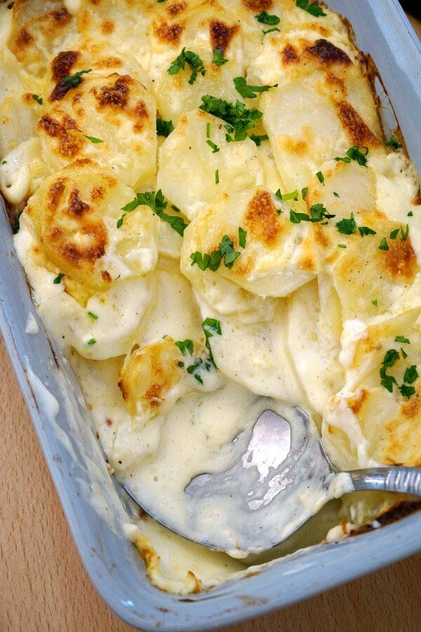 a casserole dish with potatoes and parsley on top, ready to be eaten