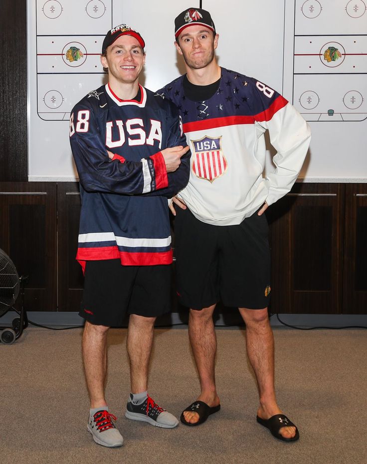 two men standing next to each other in front of a wall with hockey jerseys on it