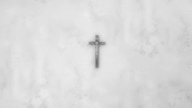 a black and white photo of a cross on a wall with snow all around it