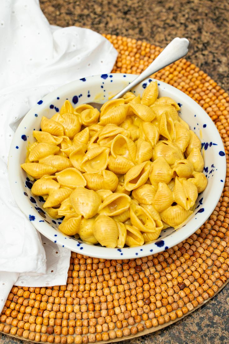 a bowl filled with macaroni and cheese on top of a wooden table next to a white towel