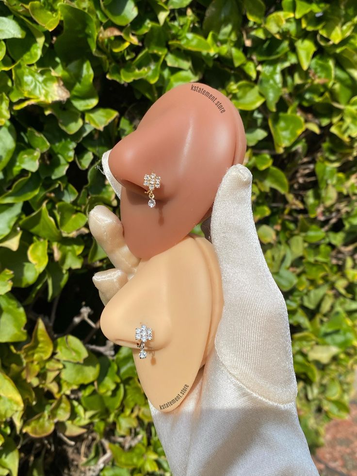 a hand is holding a fake nose with an earring on it's head