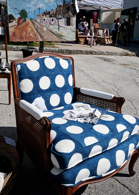 a blue and white polka dot chair sitting on the street