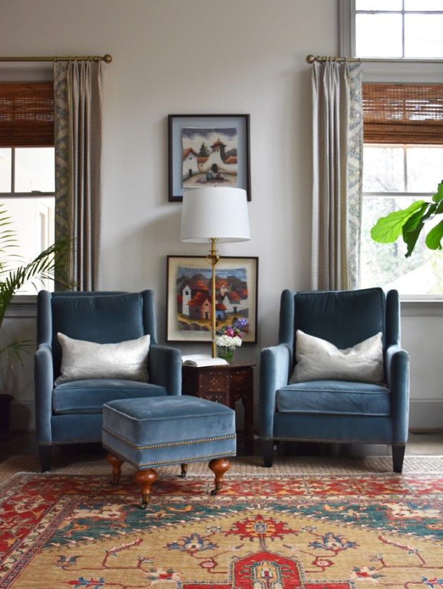 a living room with two blue chairs and a rug