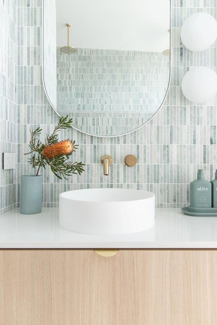 a bathroom sink sitting under a round mirror