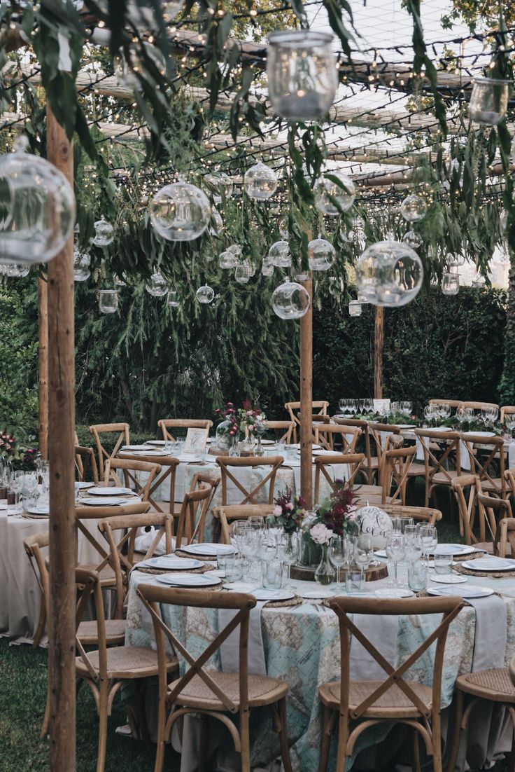 an outdoor dining area with tables, chairs and chandelier hanging from the ceiling