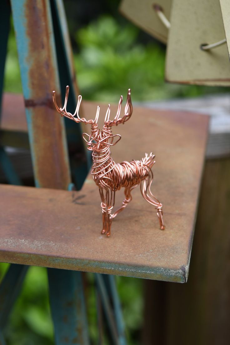 a metal deer sculpture sitting on top of a wooden table