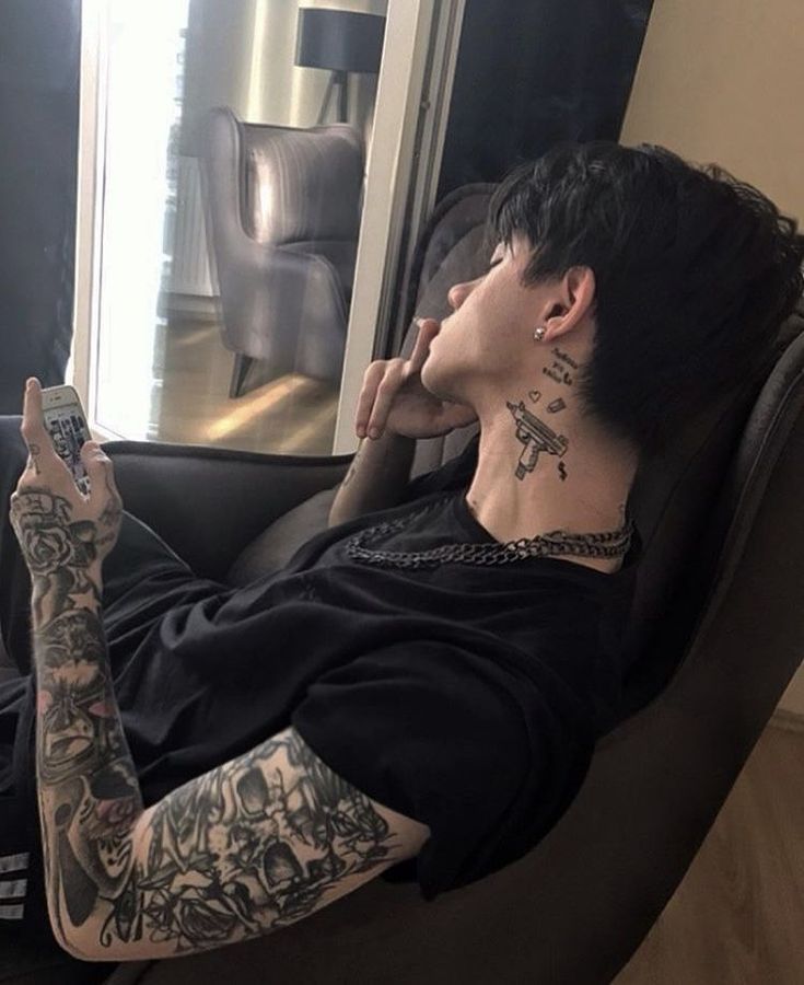 a man sitting in a chair with tattoos on his arm