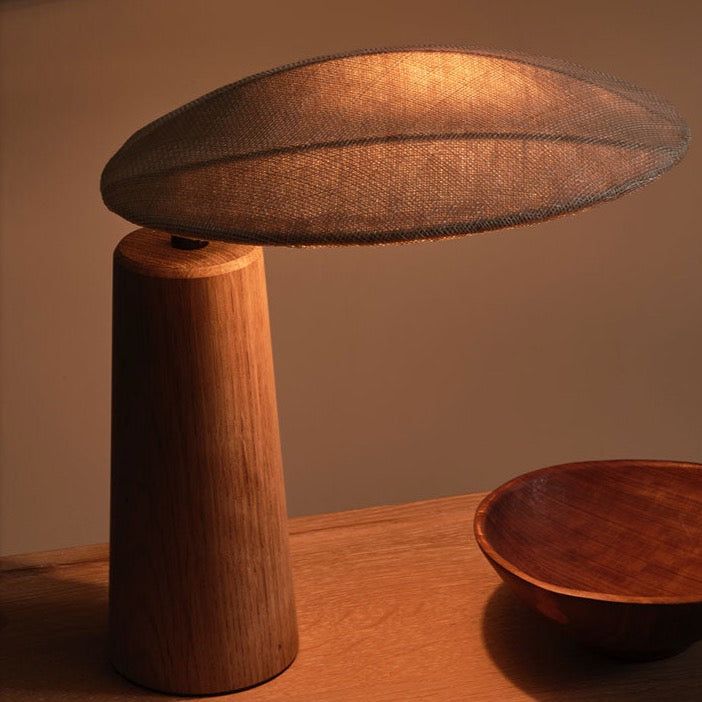 a wooden table topped with a bowl and a lamp on top of it's stand