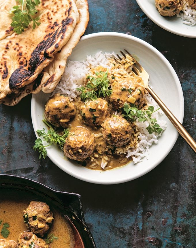 two plates with meatballs and rice next to a pita bread on a table