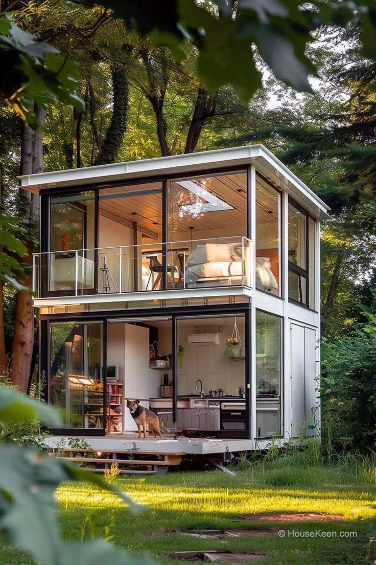 a small house in the woods with lots of windows on it's sides and an open floor plan