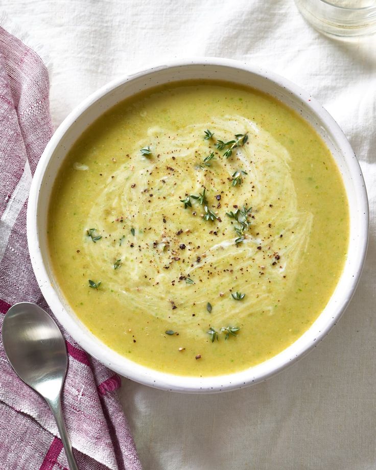 a white bowl filled with broccoli soup next to a spoon