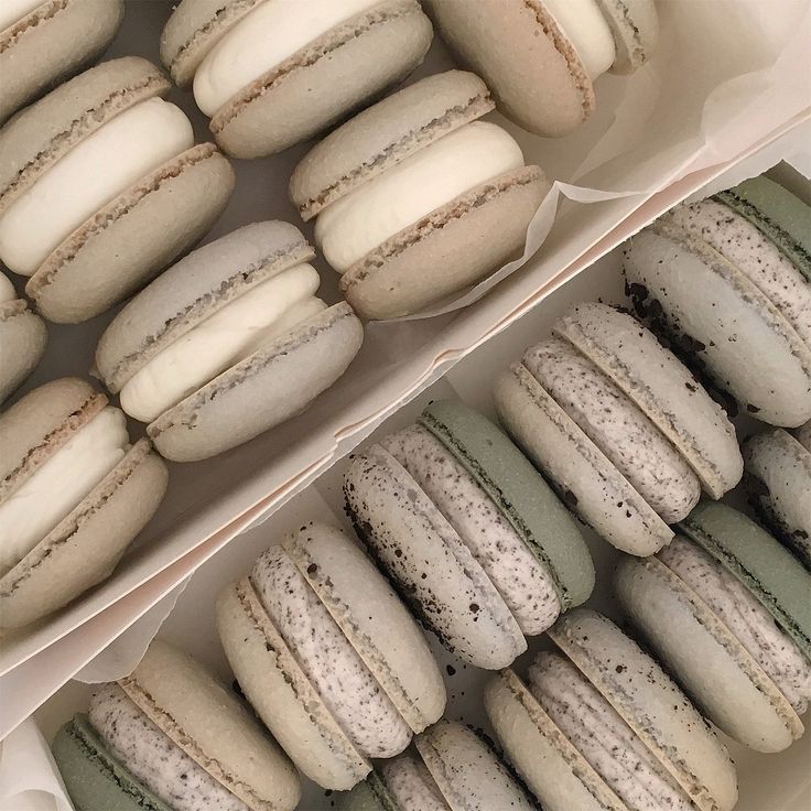 two trays filled with different types of macaroons next to eachother