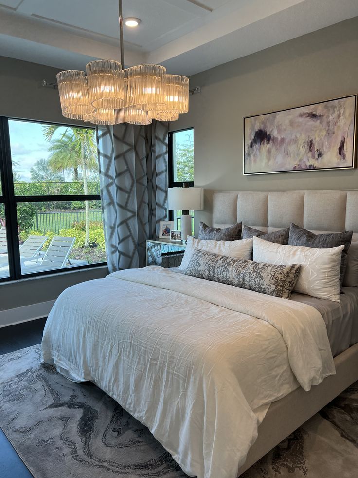 a large bed sitting in a bedroom under a chandelier next to a window